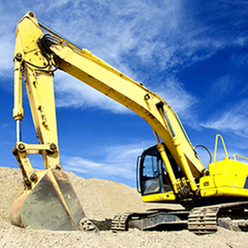 A yellow excavator at a construction site under a blue sky, used by Dahme Construction in San Jose.